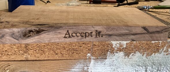 close up of wood burned shelf with text, "Accept it."