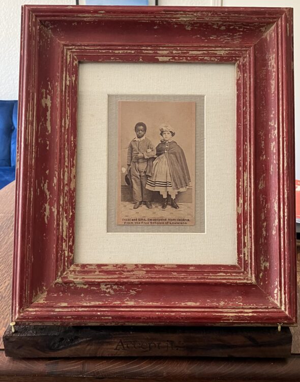 Photo of multimedia piece with archival photo of two children who were emancipated slaves, wood burned shelf with text and frame.